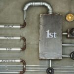 Industrial wall art featuring pipes and text on a concrete wall with a vintage style.