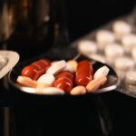 Close-up of assorted pharmaceutical pills in blister packs and a spoon on a dark background.