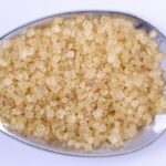 Detailed close-up of raw brown sugar on a metal spoon, perfect for food and cooking themes.