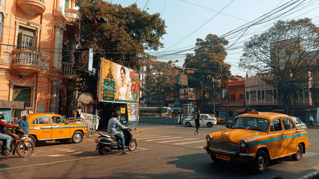 Vibrant street life in Kolkata featuring iconic yellow taxis and historic architecture.