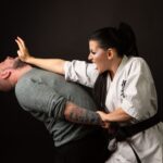 A woman in karate attire defends herself against a man in a martial arts demonstration.
