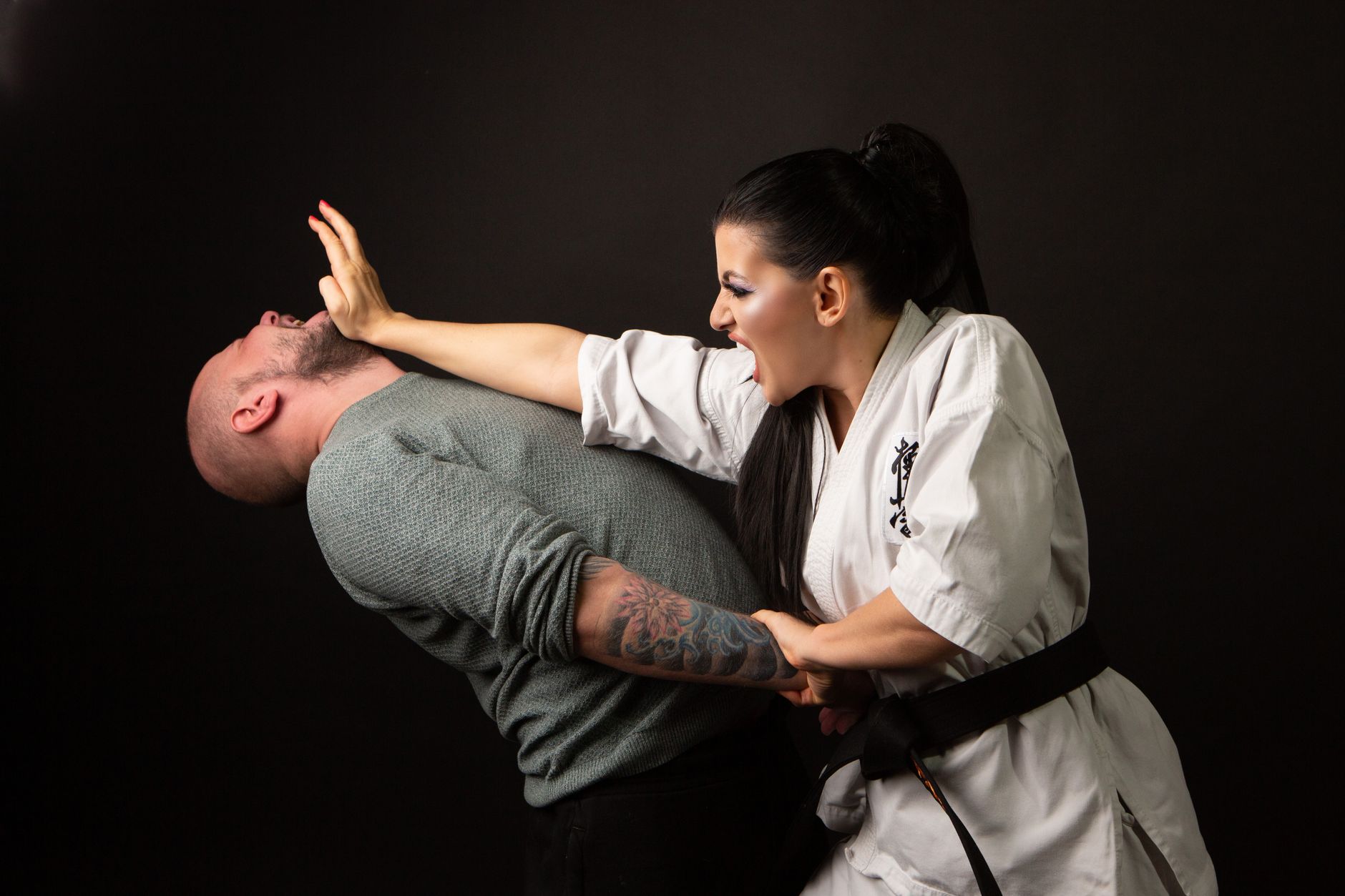 A woman in karate attire defends herself against a man in a martial arts demonstration.