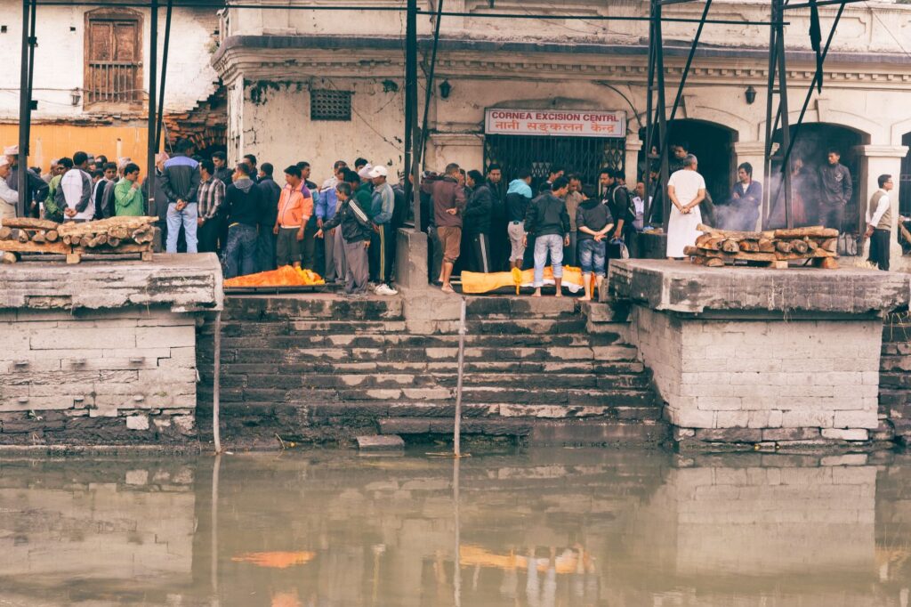 A traditional funeral ceremony taking place by a riverside in an urban setting.