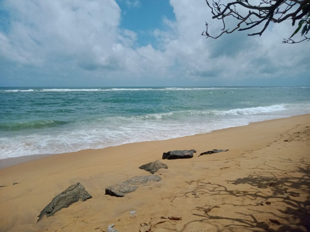 Peaceful sandy beach with gentle waves and blue sky in Colombo, Sri Lanka.