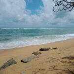 Peaceful sandy beach with gentle waves and blue sky in Colombo, Sri Lanka.