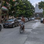 A man cycling down a street in Kanchipuram, India, near a famous temple.