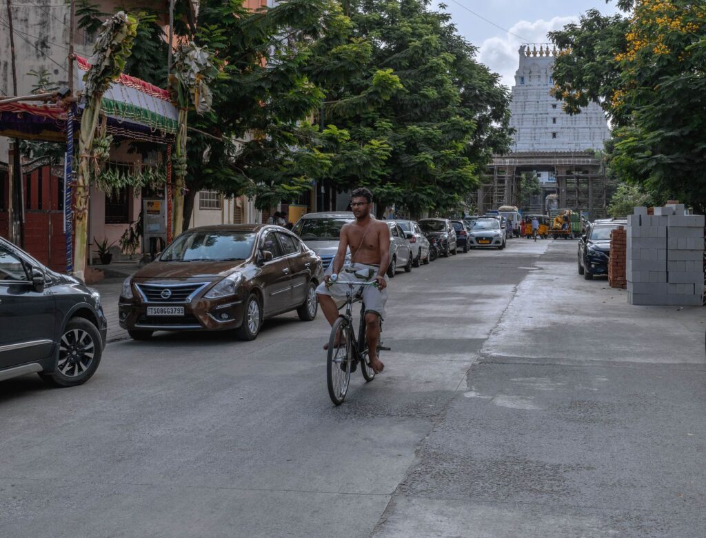 A man cycling down a street in Kanchipuram, India, near a famous temple.