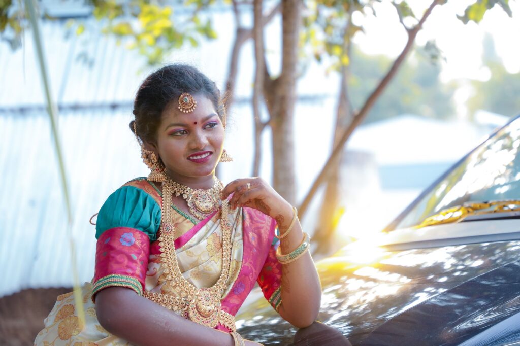 A woman in Chennai wearing a colorful sari and jewelry, smiling outdoors.