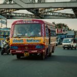 Vibrant city scene in Kolkata, India with colorful bus, vehicles, and commuters.