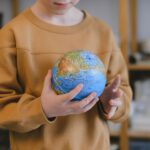 A child carefully holding a globe, symbolizing global education and exploration.