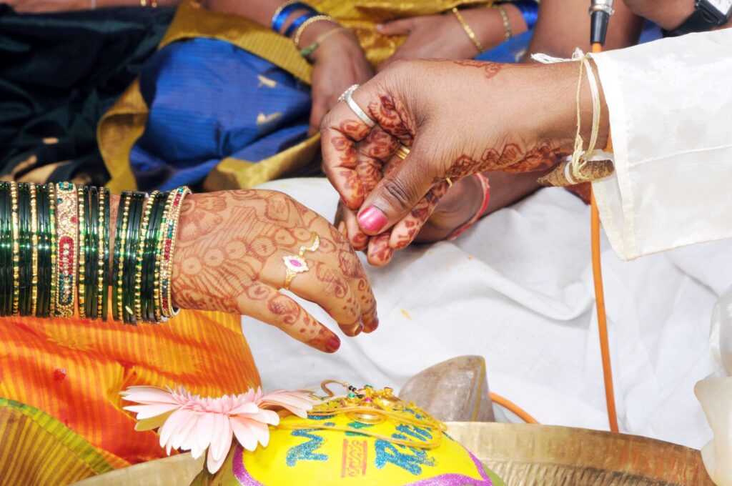 Close-up of hands in a traditional Indian wedding ceremony with intricate henna designs.