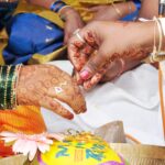 Close-up of hands in a traditional Indian wedding ceremony with intricate henna designs.