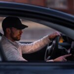 A man interacts with a touchscreen inside an electric car, driving through Dallas, TX.