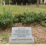 Memorial stone for 9/11 victims surrounded by roses in a peaceful park.