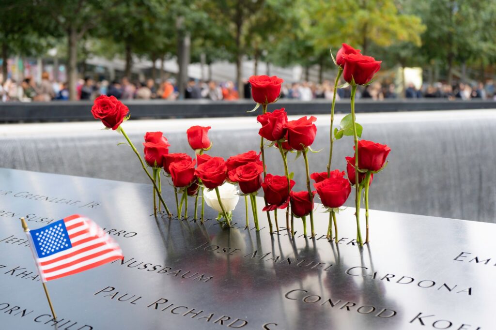 Red roses and American flag at 9/11 Memorial in New York City, reflecting remembrance.