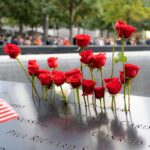 Red roses and American flag at 9/11 Memorial in New York City, reflecting remembrance.