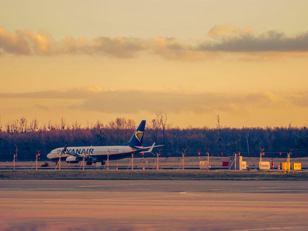 A Ryanair plane at Wrocław Airport at sunset with warm lighting and clear skies.