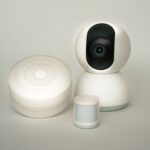 Modern smart home devices including a camera and sensors on a neutral background.