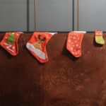 Four decorative Christmas stockings hanging indoors with festive patterns. Perfect for holiday decor inspiration.