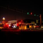 A crowded urban nighttime scene featuring a traffic accident at a busy intersection.