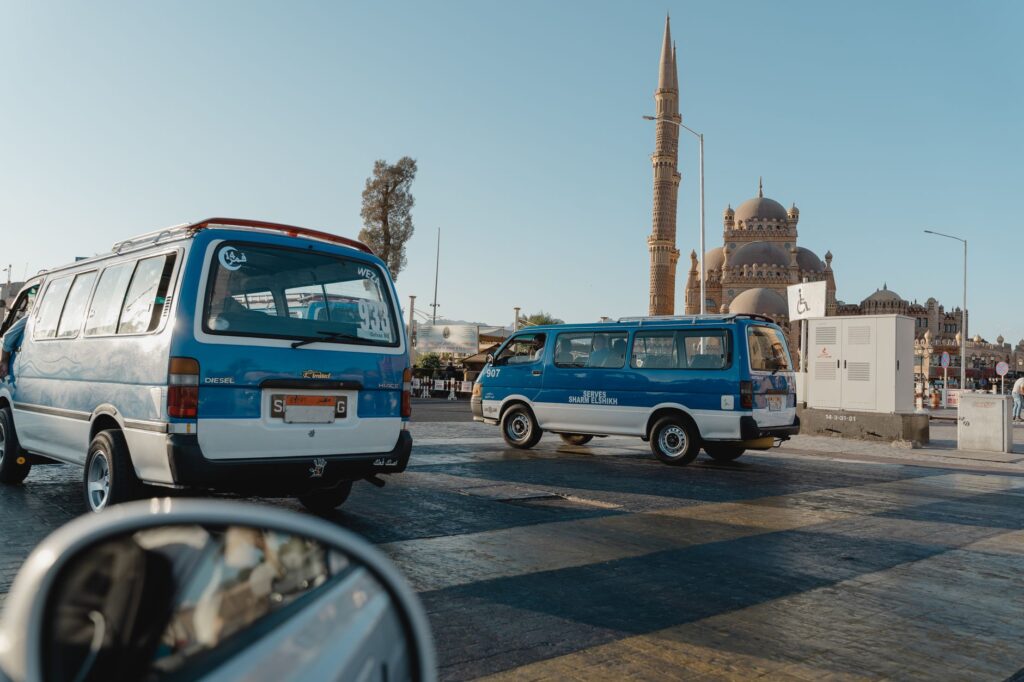 View of a city street featuring a mosque and parked minivans under clear skies.