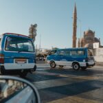 View of a city street featuring a mosque and parked minivans under clear skies.