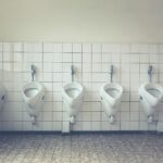 A modern and tidy restroom with a row of white urinals and tiled walls and floors.