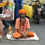 An Indian Sadhu in traditional attire meditates on a street in Jabalpur, India.