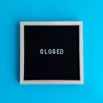 A letter board with 'Closed' displayed against a vibrant blue backdrop, signifying a closure or notice.