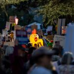 A vibrant protest scene capturing various signs and symbols in downtown Sacramento.