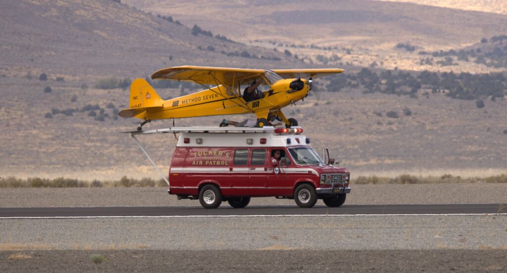 Unique scene of yellow plane mounted on red van, outdoors.