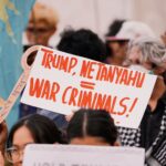Protesters hold signs at a rally, expressing political views and dissent.