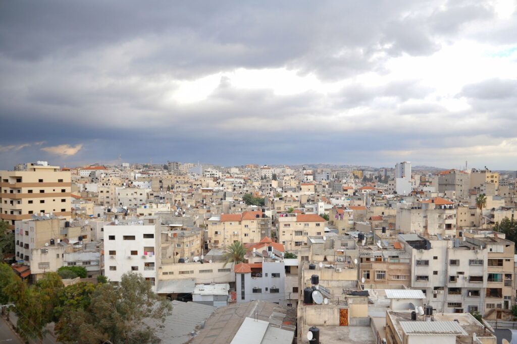Aerial view of Qalqilya's urban cityscape under dramatic clouds, showcasing diverse architecture.