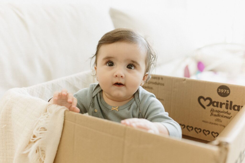 Cute baby in a cardboard box at home, capturing playful expressions indoor.
