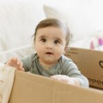 Cute baby in a cardboard box at home, capturing playful expressions indoor.