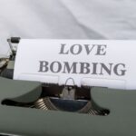 Close-up of a typewriter displaying the phrase 'Love Bombing' on paper.