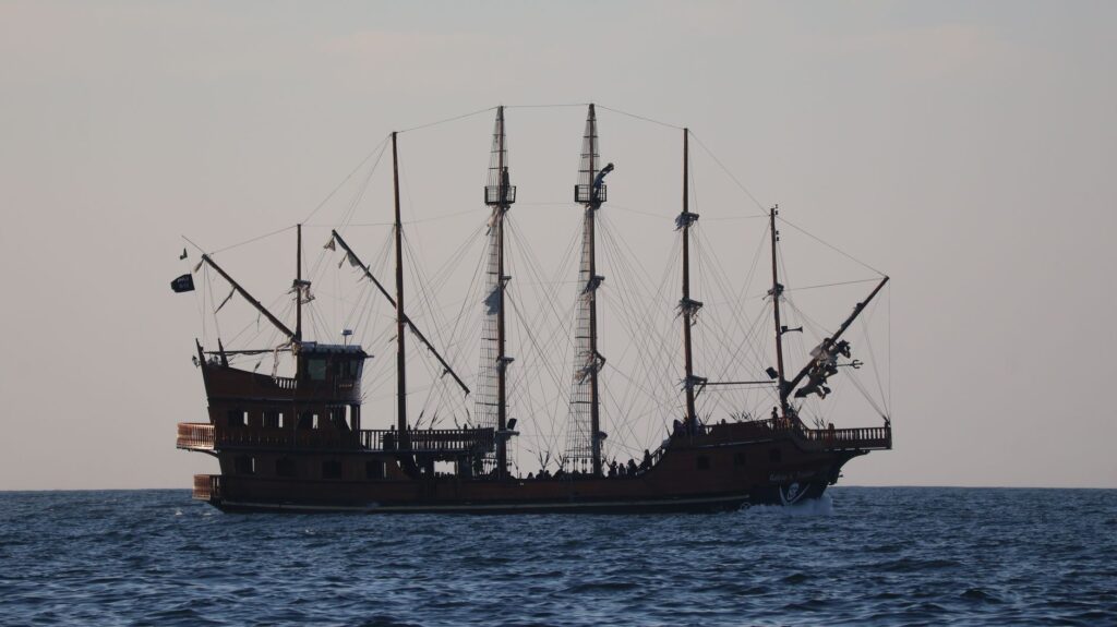 A grand pirate ship with full sails navigating the scenic ocean near Balneário Camboriú, Brazil.