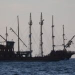 A grand pirate ship with full sails navigating the scenic ocean near Balneário Camboriú, Brazil.
