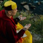 A monk meditating on a riverbank, capturing spiritual tranquility and nature's beauty.