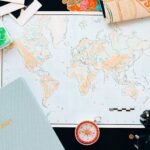 Flat lay of travel essentials including a world map, compass, and planner, perfect for planning your next adventure.