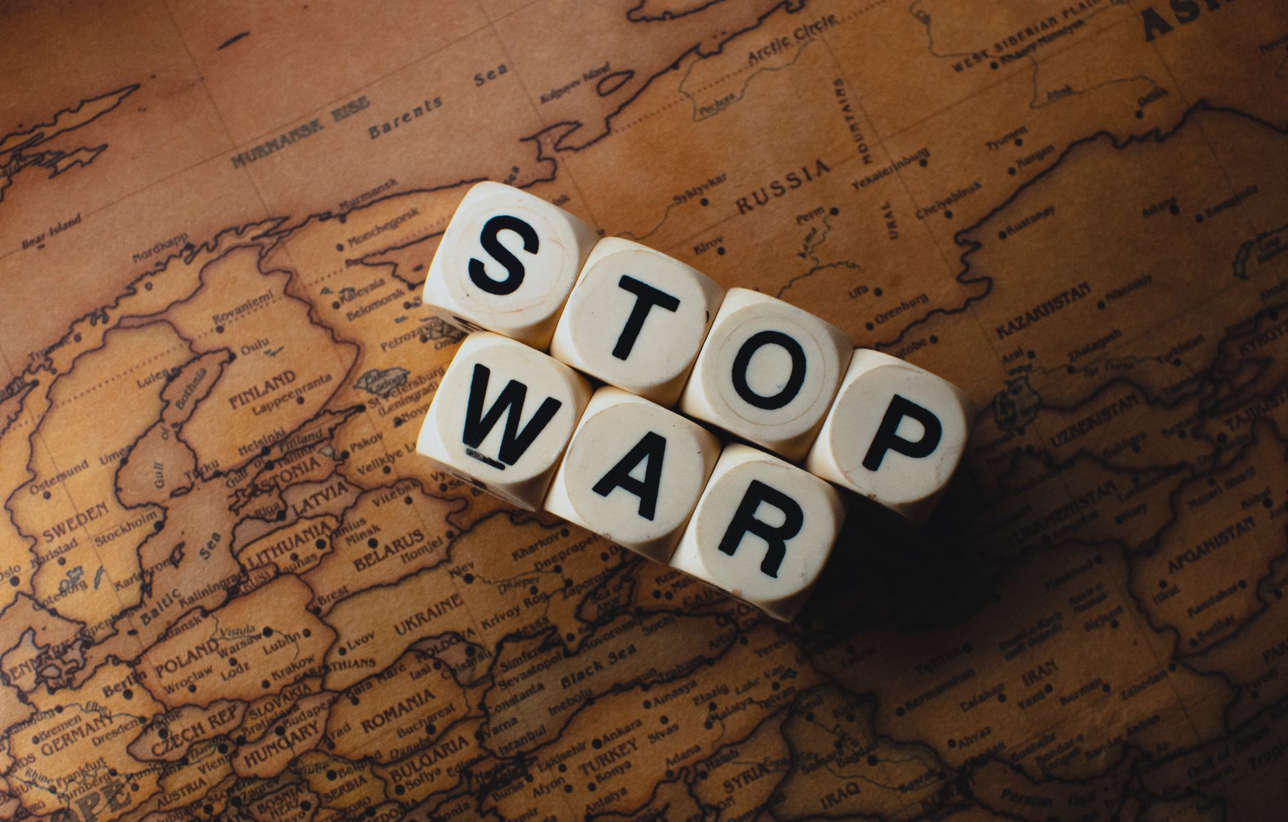 Dice with 'STOP WAR' on a vintage world map signifies peace.
