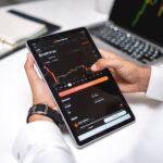 Professional analyzing cryptocurrency market data on a digital tablet with financial graphs.