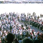 A large crowd gathers outdoors under sunny conditions in Saudi Arabia.