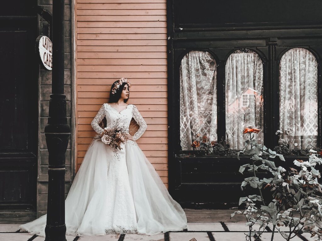 A bride in a stylish gown poses elegantly against a classic urban backdrop in Tehran.