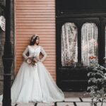 A bride in a stylish gown poses elegantly against a classic urban backdrop in Tehran.