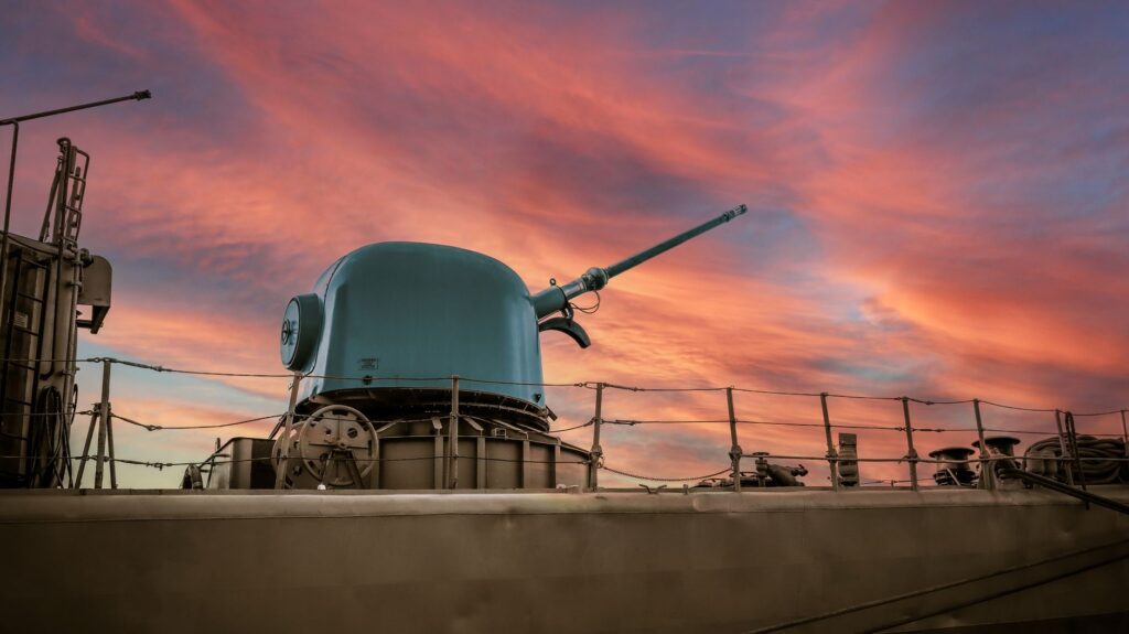 A military battleship showcased against a vibrant pink sunset in Málaga, España.