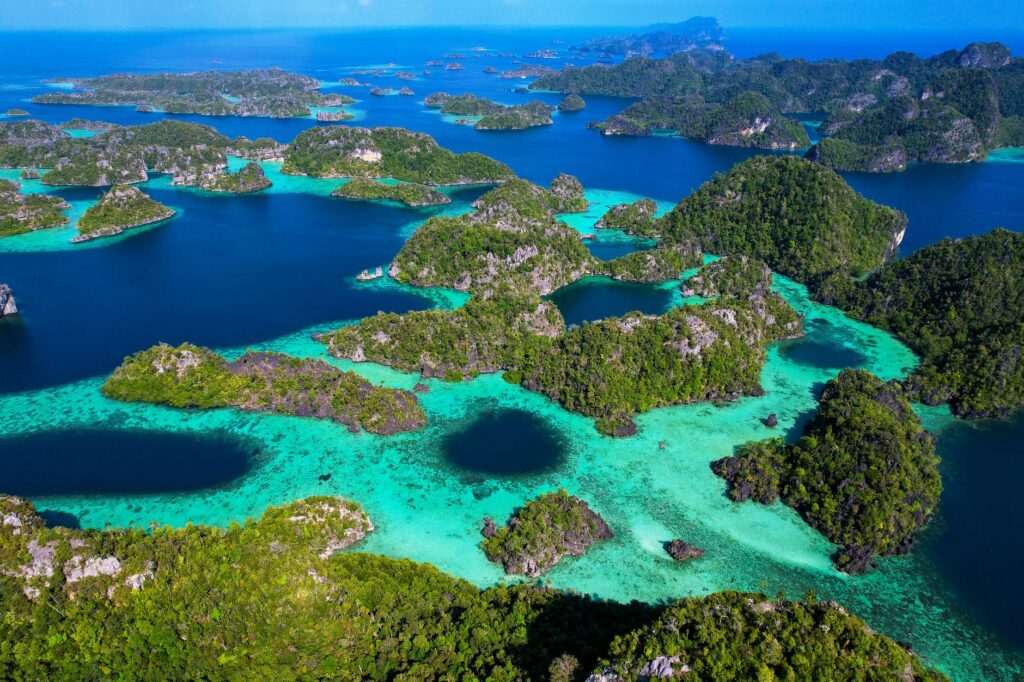 Breathtaking aerial view of lush green islands and turquoise waters in Raja Ampat, Indonesia.