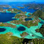 Breathtaking aerial view of lush green islands and turquoise waters in Raja Ampat, Indonesia.