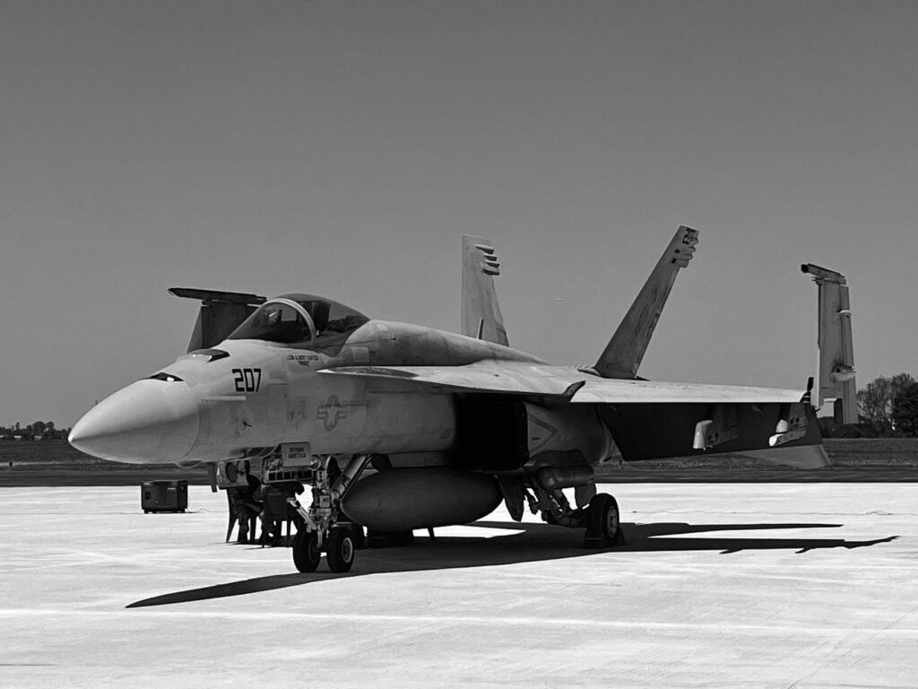 F A-18 Hornet jet parked on a tarmac captured in black and white at an airshow.