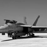 F A-18 Hornet jet parked on a tarmac captured in black and white at an airshow.